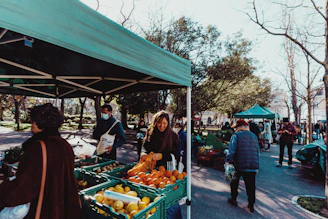 a group of people standing around a fruit stand