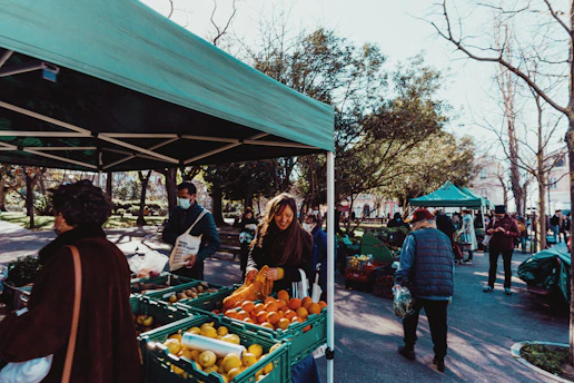 a group of people standing around a fruit stand