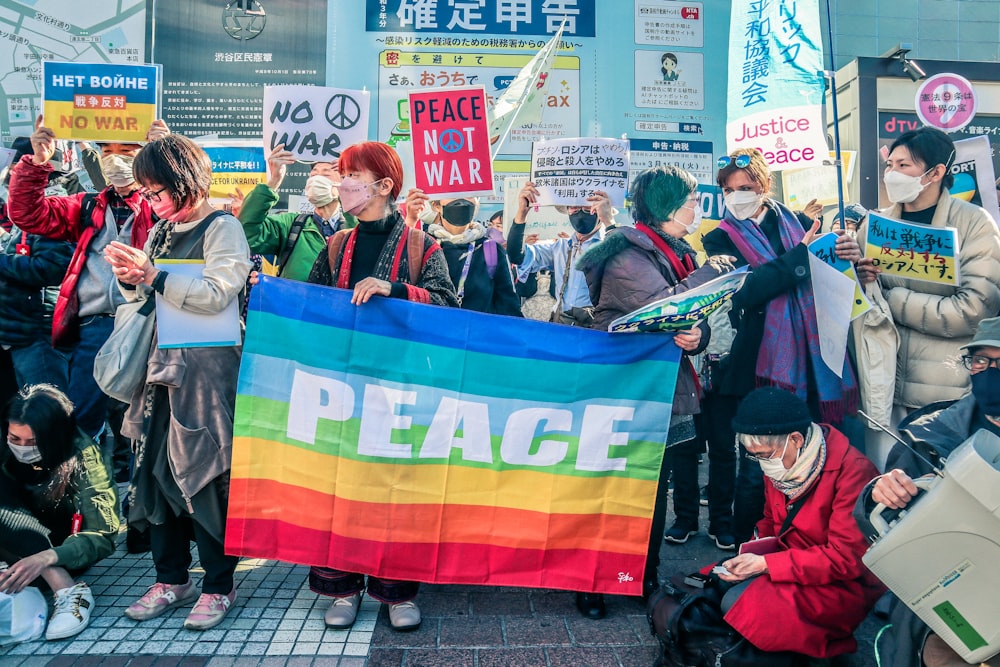 a group of people holding signs and a rainbow flag