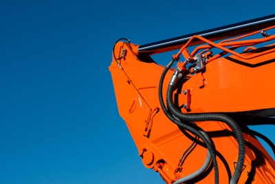 a close up of an orange crane with a sky background