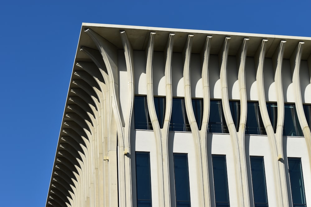 a tall building with curved windows and a blue sky in the background