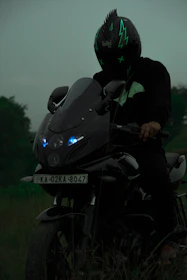 An urban rider in neon gear leaning against a customized bike with glowing electric blue accents at dusk.