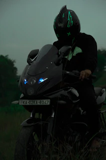 An urban rider in neon gear leaning against a customized bike with glowing electric blue accents at dusk.