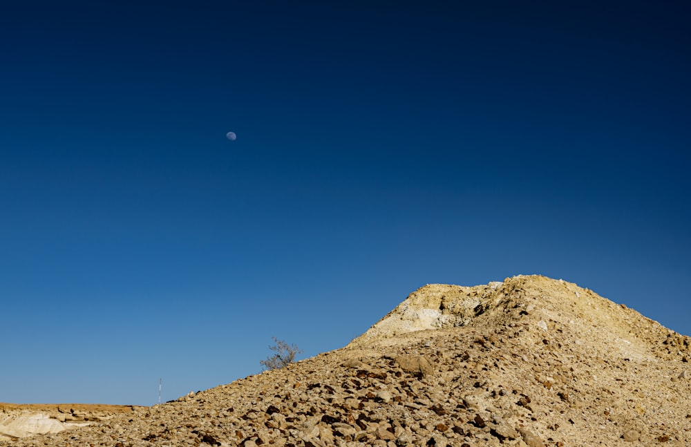 a hill of dirt with a moon in the sky