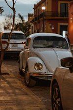 A classic vintage Volkswagen Beetle parked on a cobblestone street with sunlight casting warm shadows.
