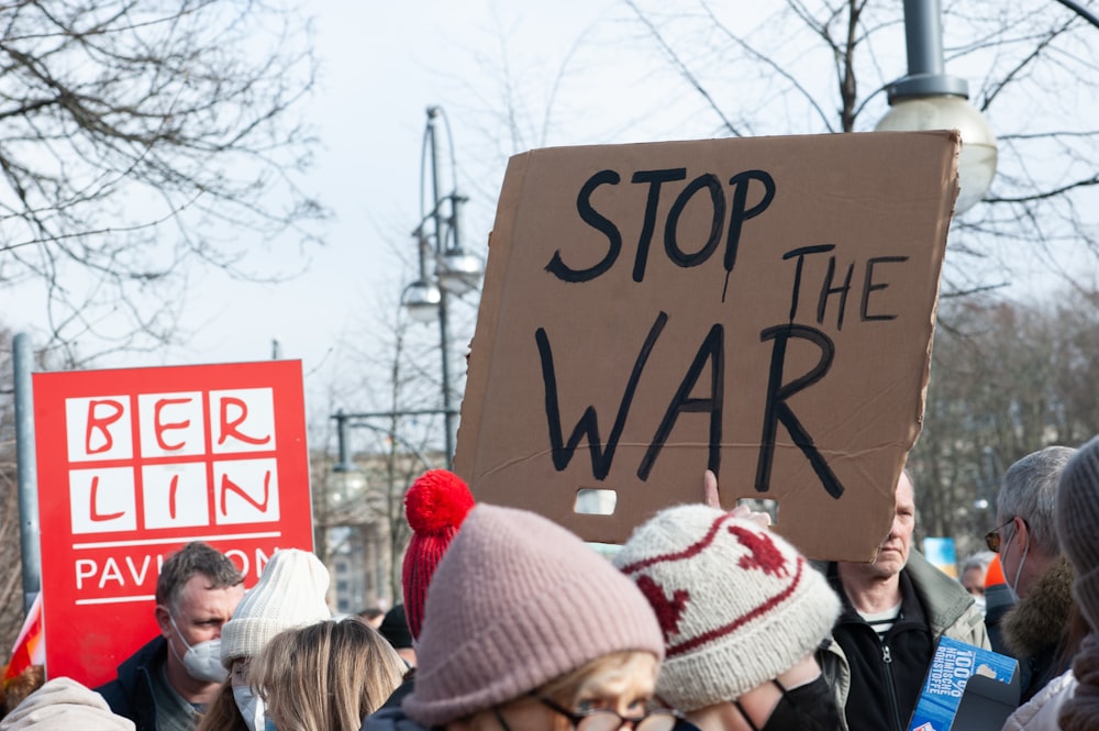 a group of people holding signs and wearing winter hats