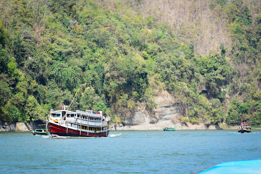 a boat traveling down a river next to a lush green hillside