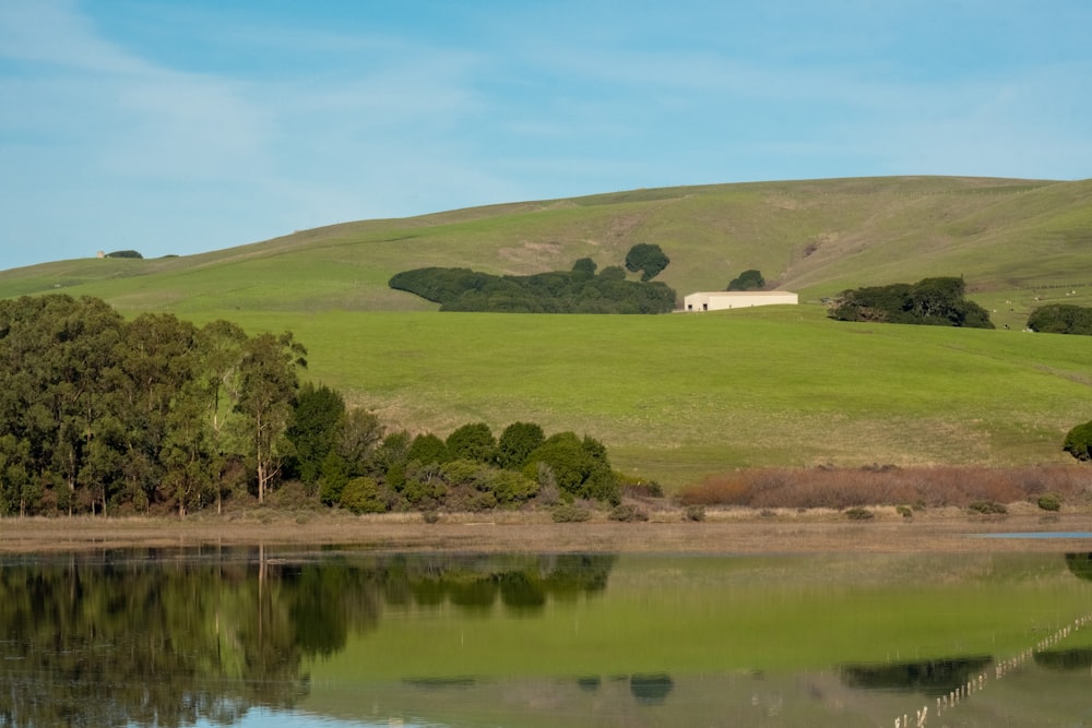 a grassy hill with a lake in front of it