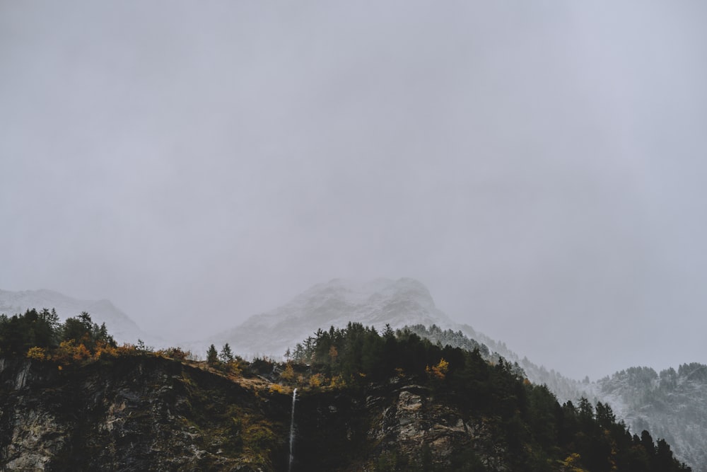 a foggy mountain with a waterfall in the foreground