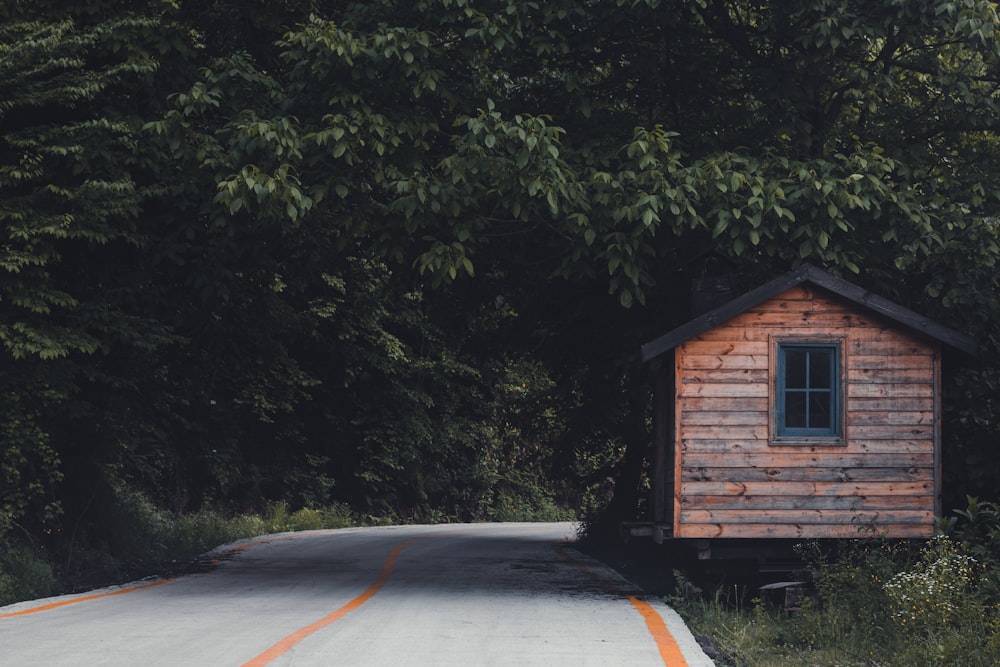 a small wooden cabin sitting on the side of a road