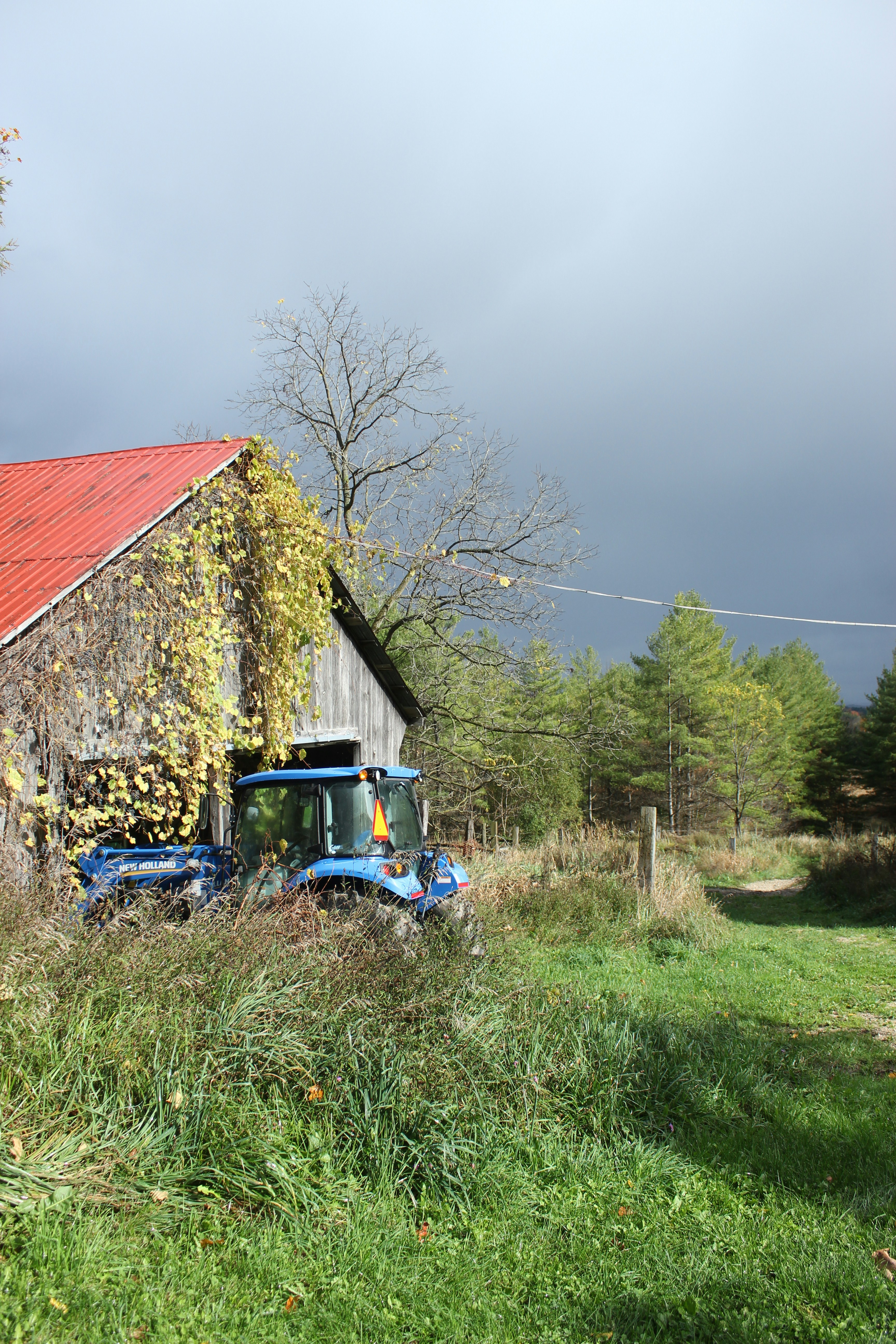 a blue tractor parked in front of a barn