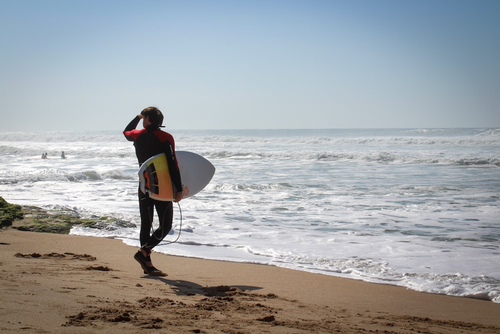a man holding a surfboard on top of a sandy beach