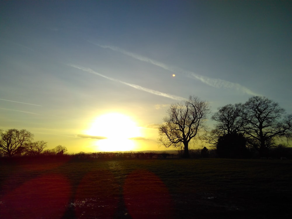 the sun is setting over a grassy field