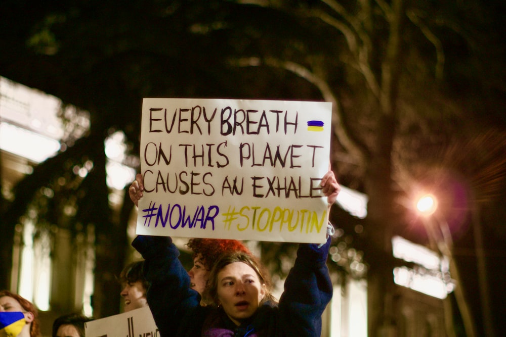 a woman holding a sign that says every breath on this planet cause an exhale