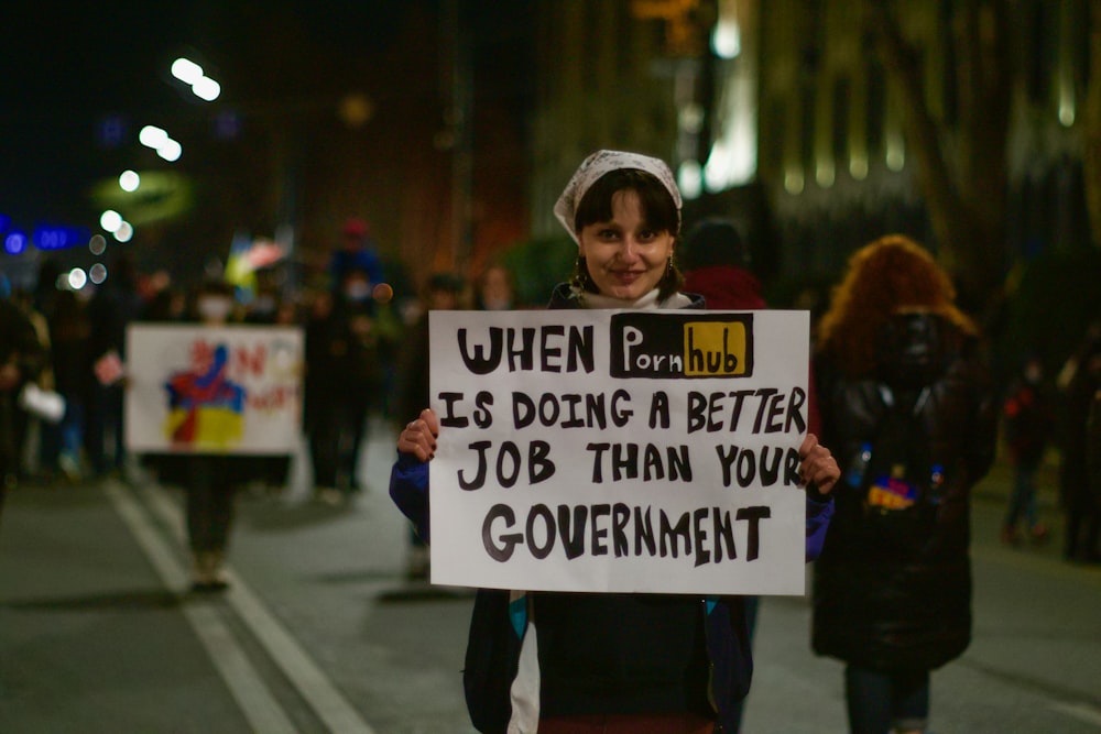 a woman holding a sign that says when it's doing a better job than
