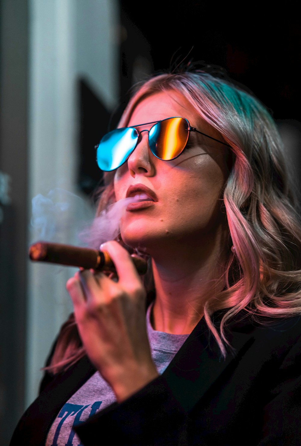 a woman smoking a cigarette wearing sunglasses