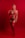 A woman stands confidently against a vibrant red backdrop, wearing red lingerie. The lighting emphasizes the striking color, casting an intense and dramatic tone to the composition. Her pose is poised and self-assured, with one hand resting on her hip and the other touching her shoulder.