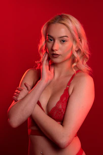 A glamorous webcam model posing confidently with vibrant lighting.