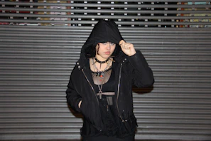 Editorial shot of layered gothic-inspired streetwear with dramatic shadows.