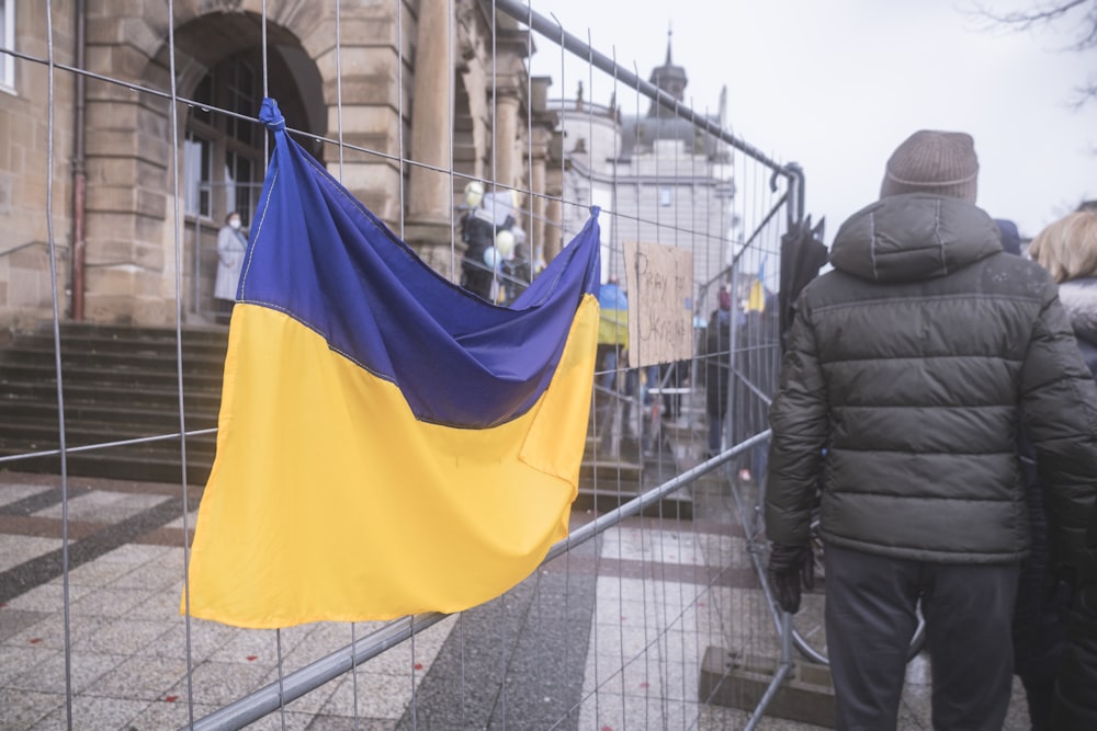 a yellow and blue flag hanging on a fence