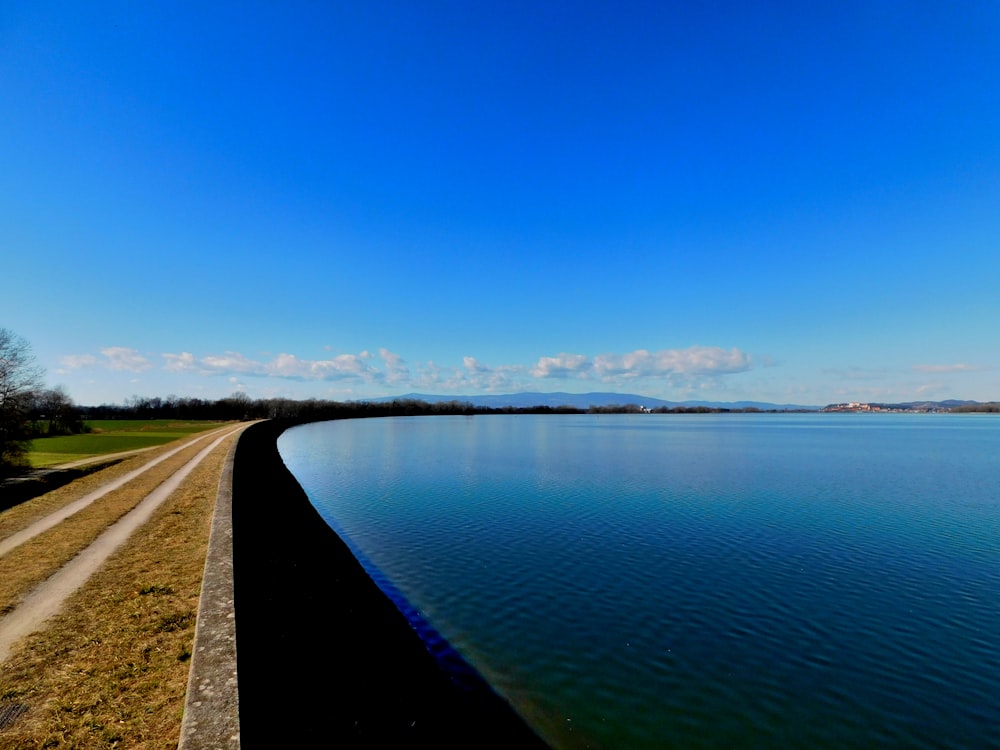 a large body of water sitting next to a lush green field