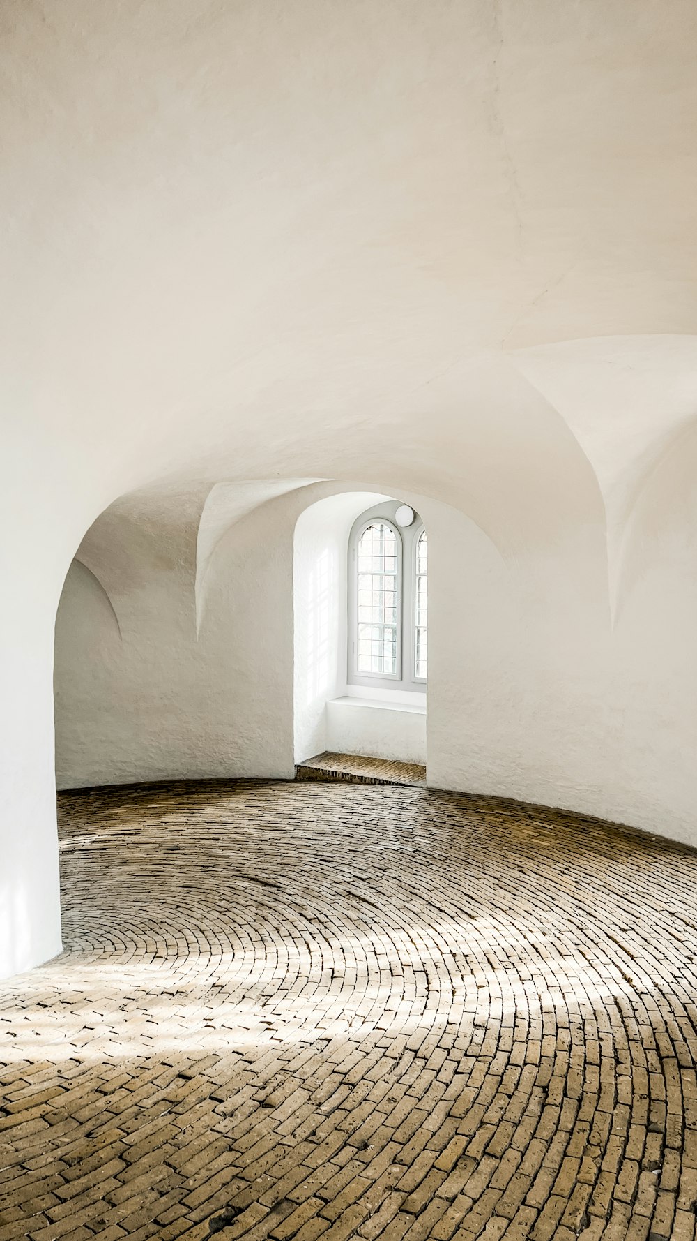 an empty room with a brick floor and arched windows