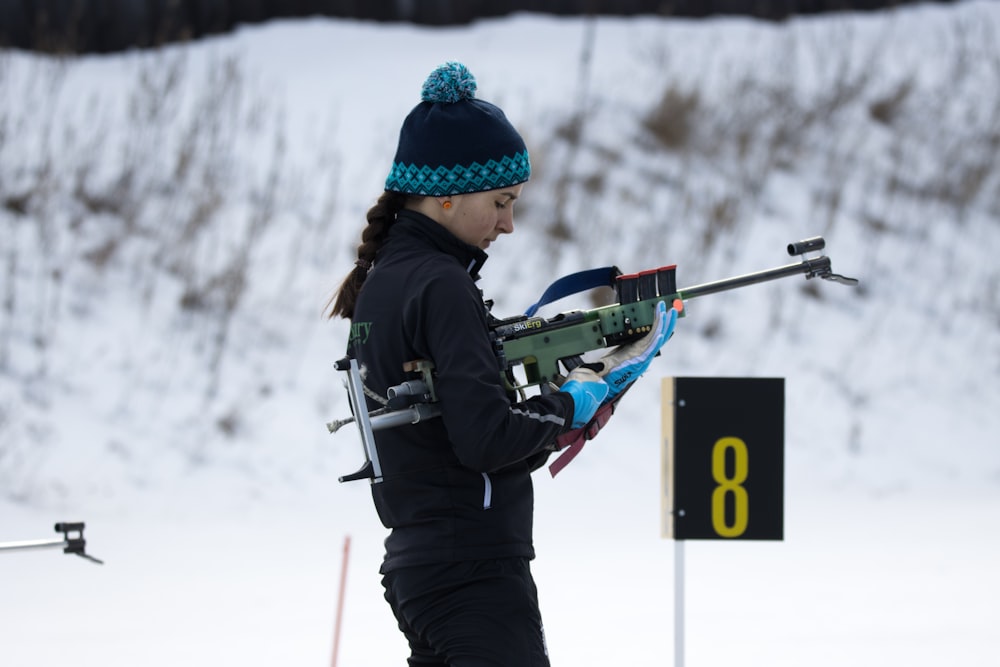 a woman holding a rifle while standing in the snow