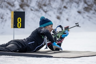 a person laying on a snow covered ground with a rifle
