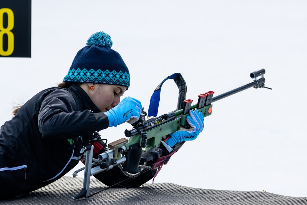 a woman with a hat and gloves is aiming a rifle