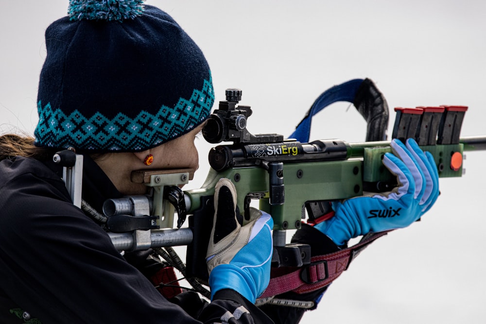 a woman with a hat and gloves holding a rifle