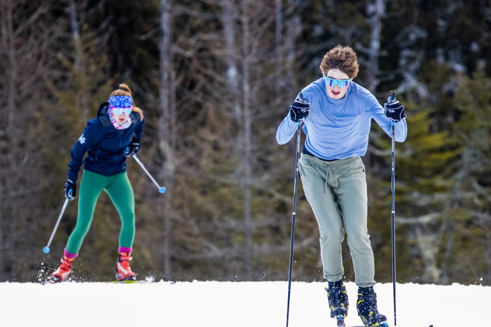 a couple of people riding skis down a snow covered slope