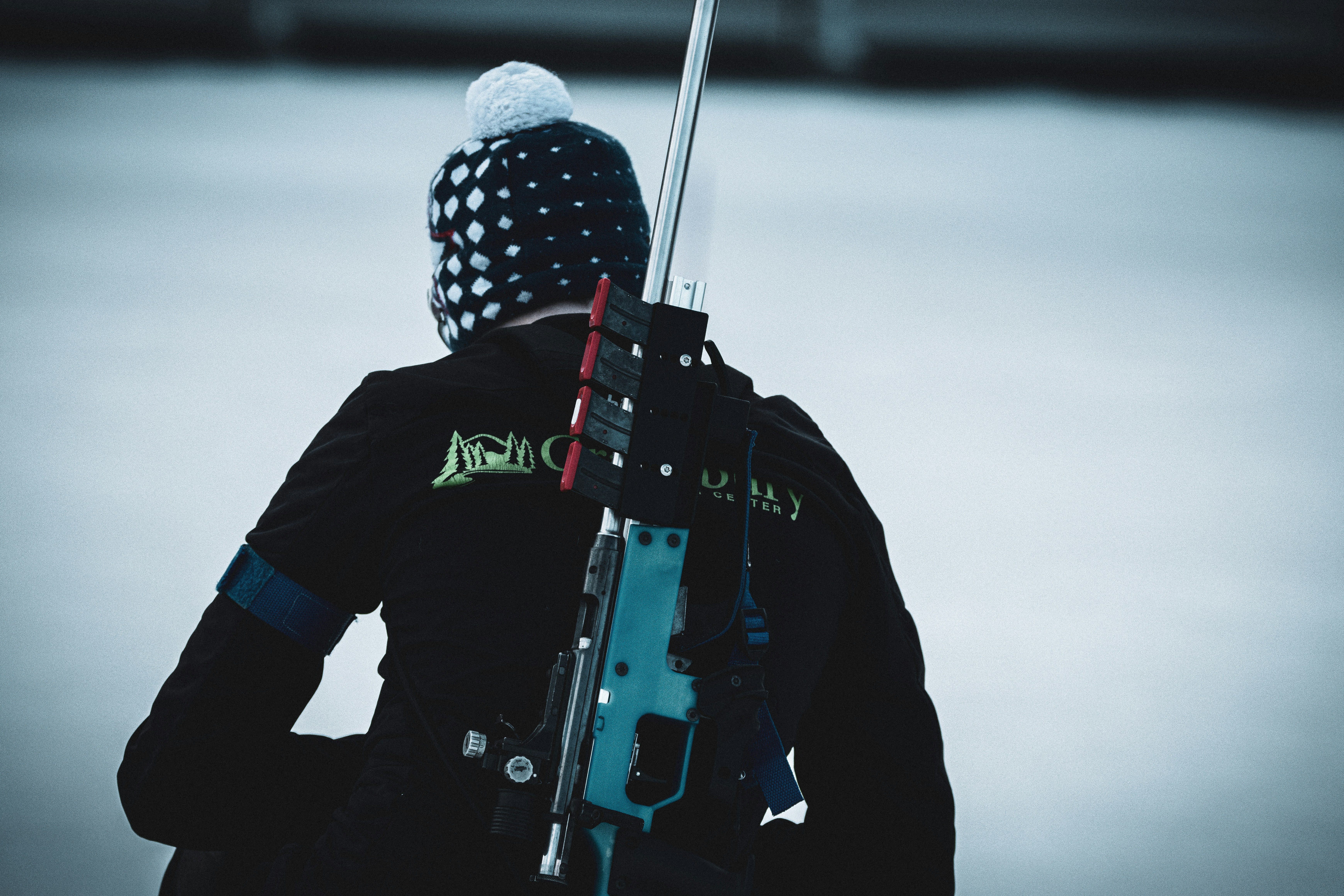 a man in a black jacket holding a rifle, 