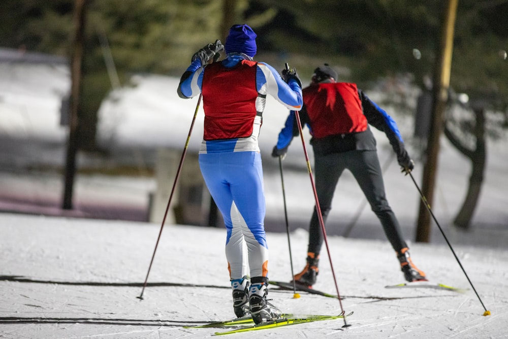 a couple of people riding skis down a snow covered slope