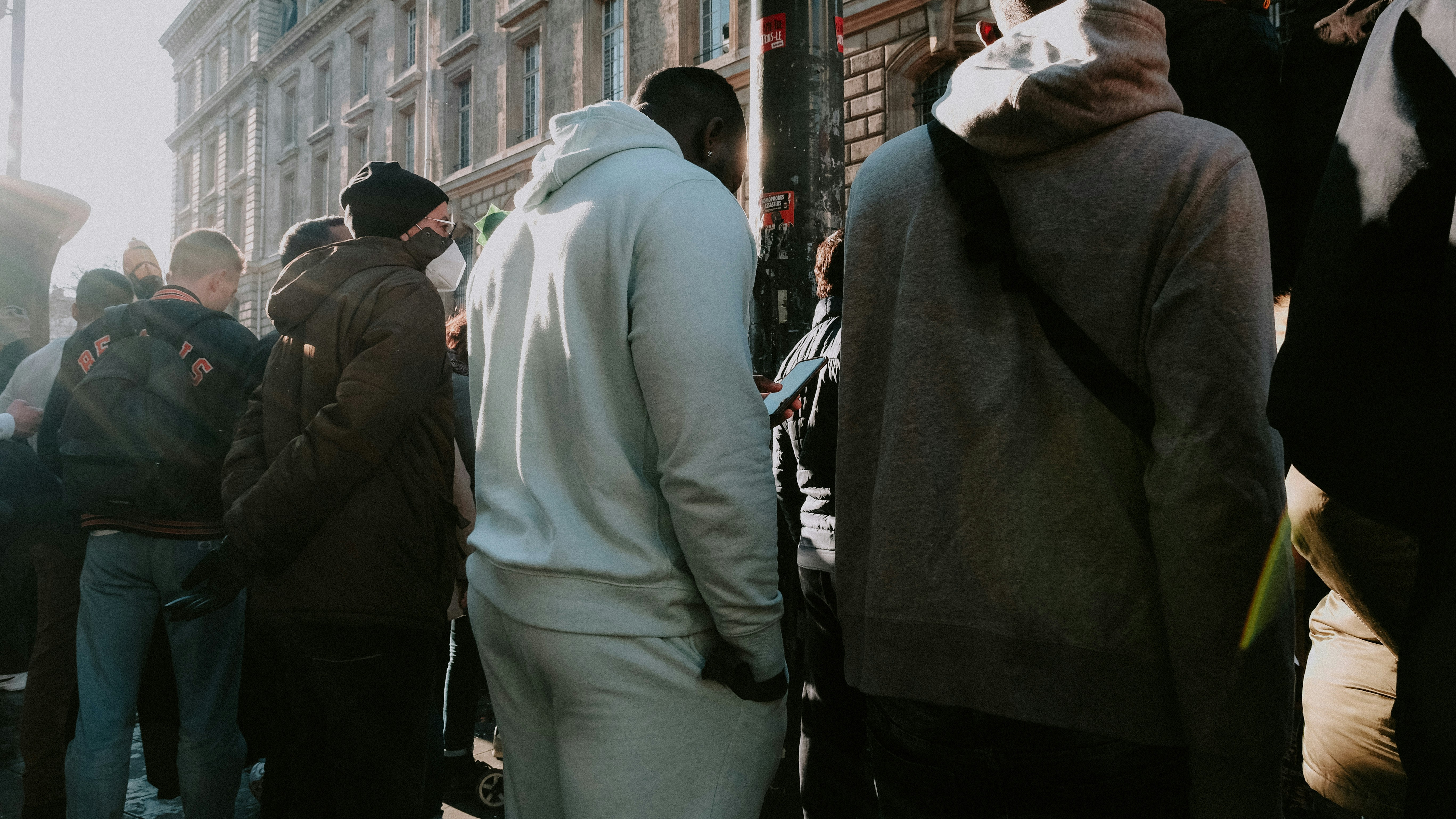 a group of people standing on a sidewalk next to a building