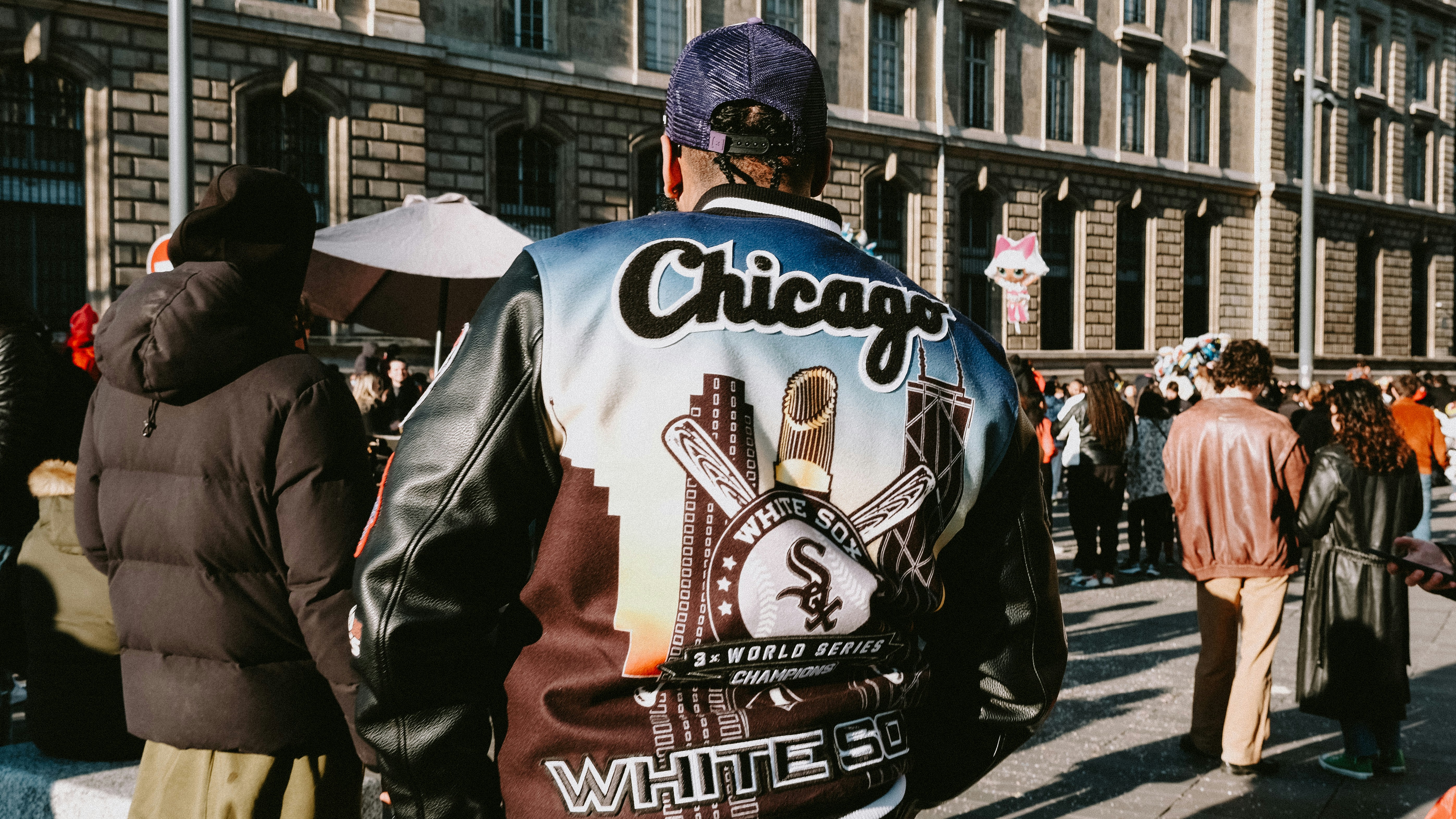 a man in a chicago baseball jacket walking down the street