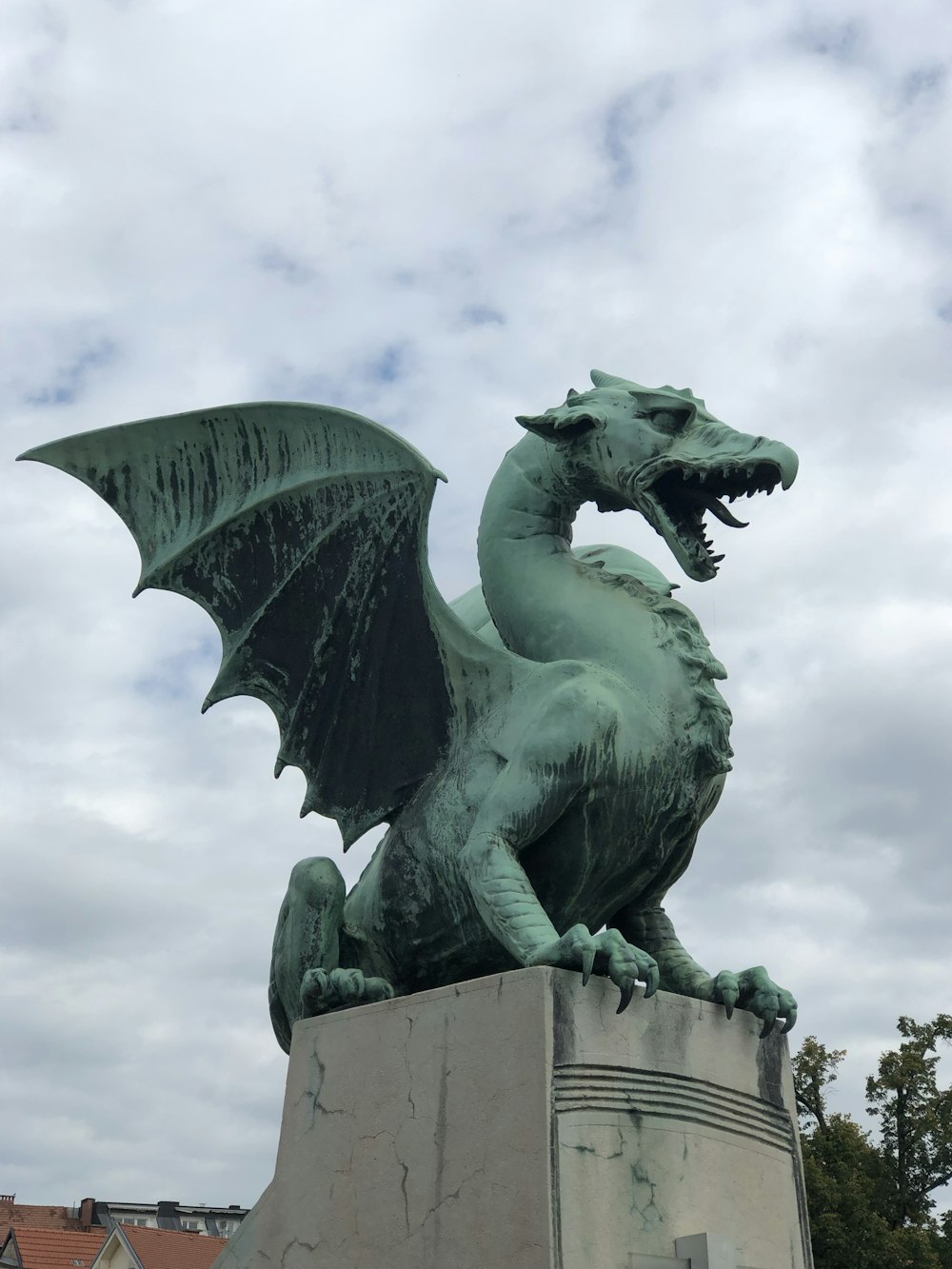 Une statue d’un dragon vert sur un piédestal