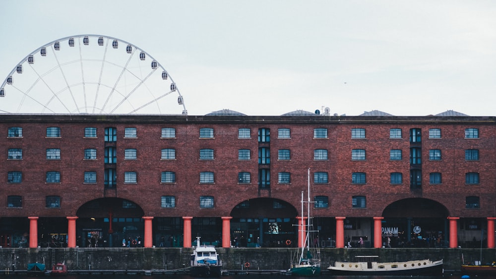 a large brick building with a ferris wheel in the background