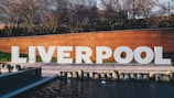 a large sign that says liverpool next to a body of water