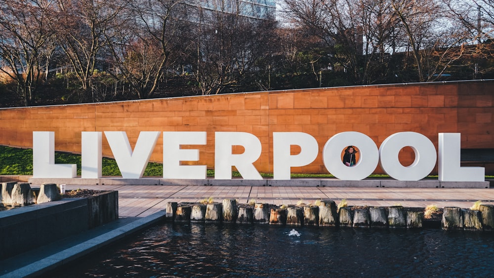 a large sign that says liverpool next to a body of water