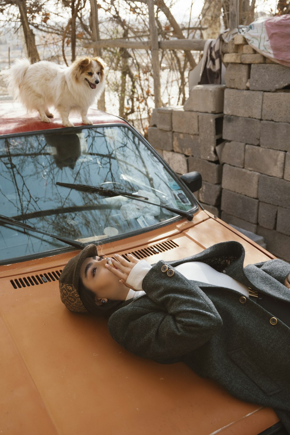 a woman laying on top of a car next to a dog