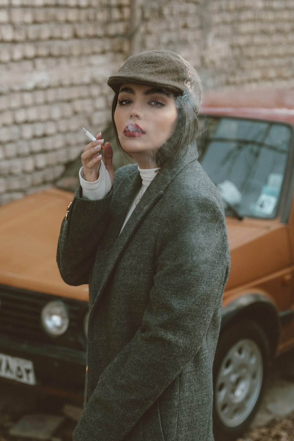 a woman smoking a cigarette in front of a car
