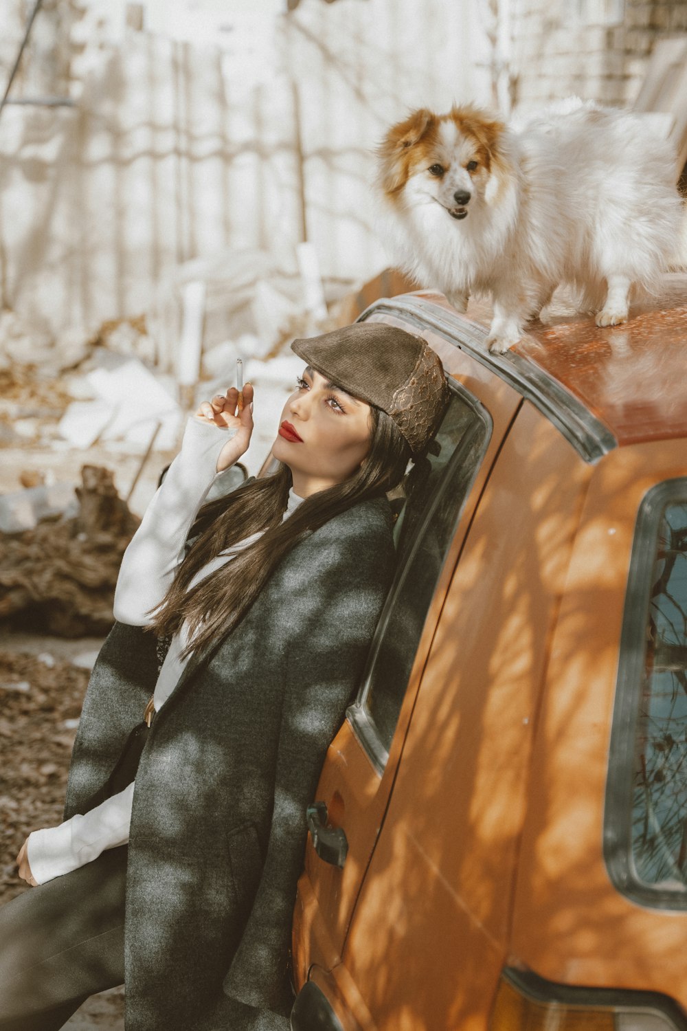a woman leaning on a car with a dog on top of her