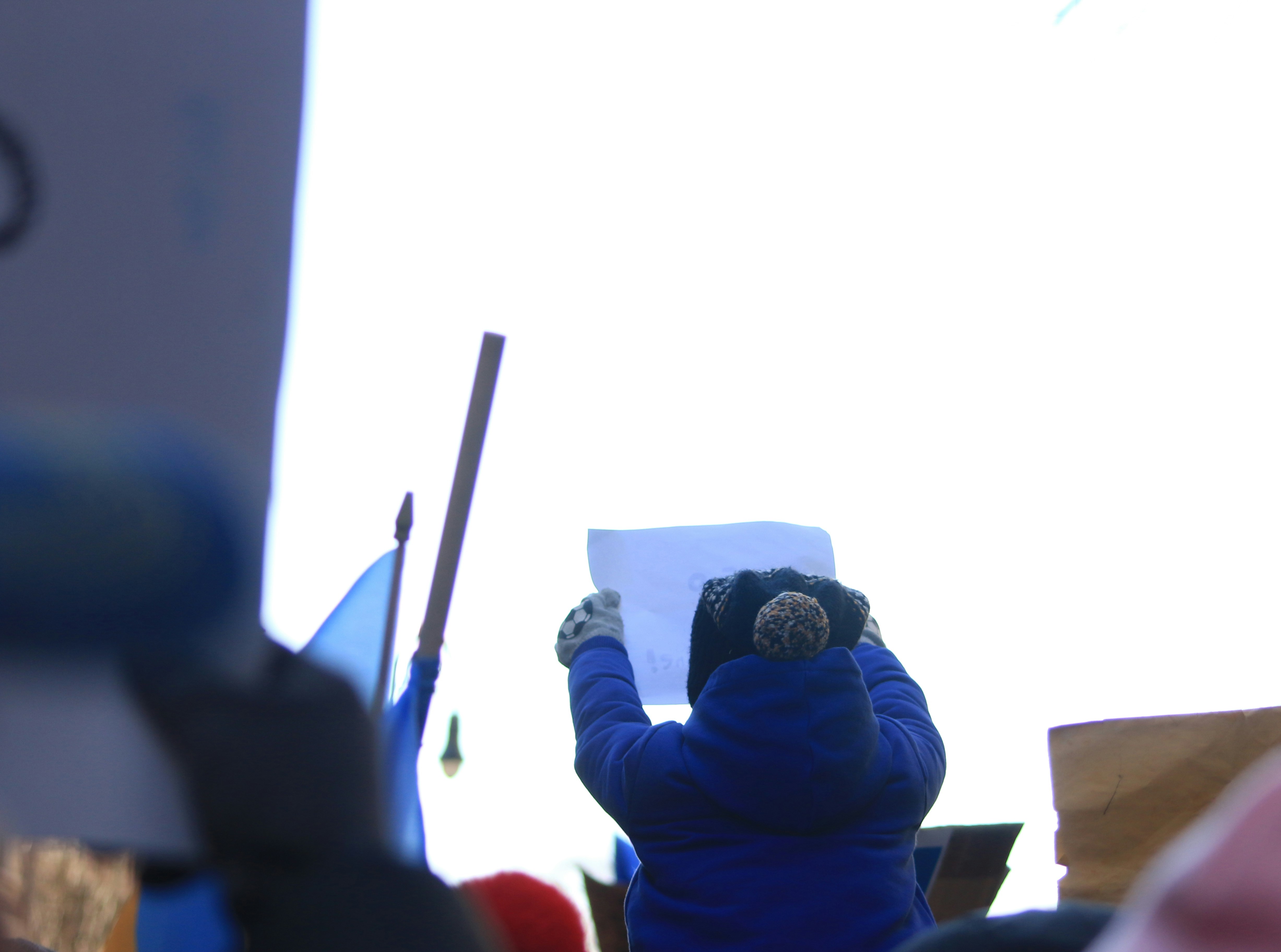 seseorang dengan jaket biru memegang tanda
