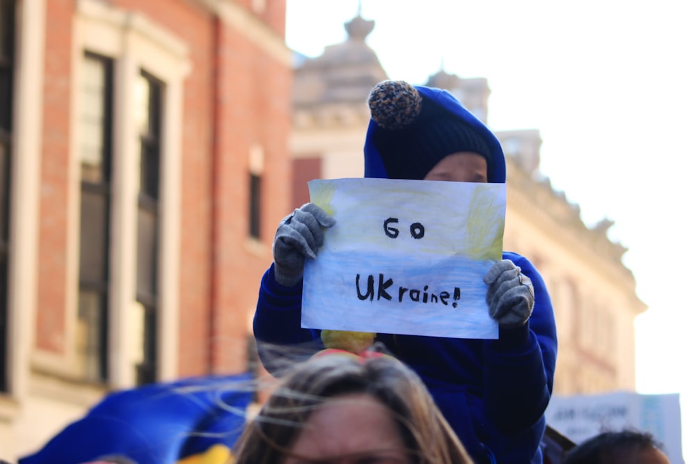 Una mujer sosteniendo un cartel que dice Go Ukraine