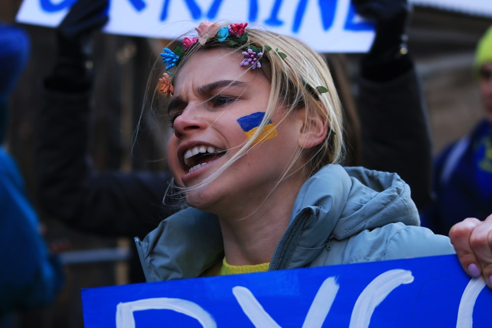 a woman with painted face holding a sign