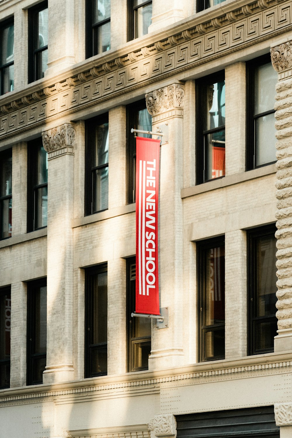 a red sign hanging from the side of a tall building