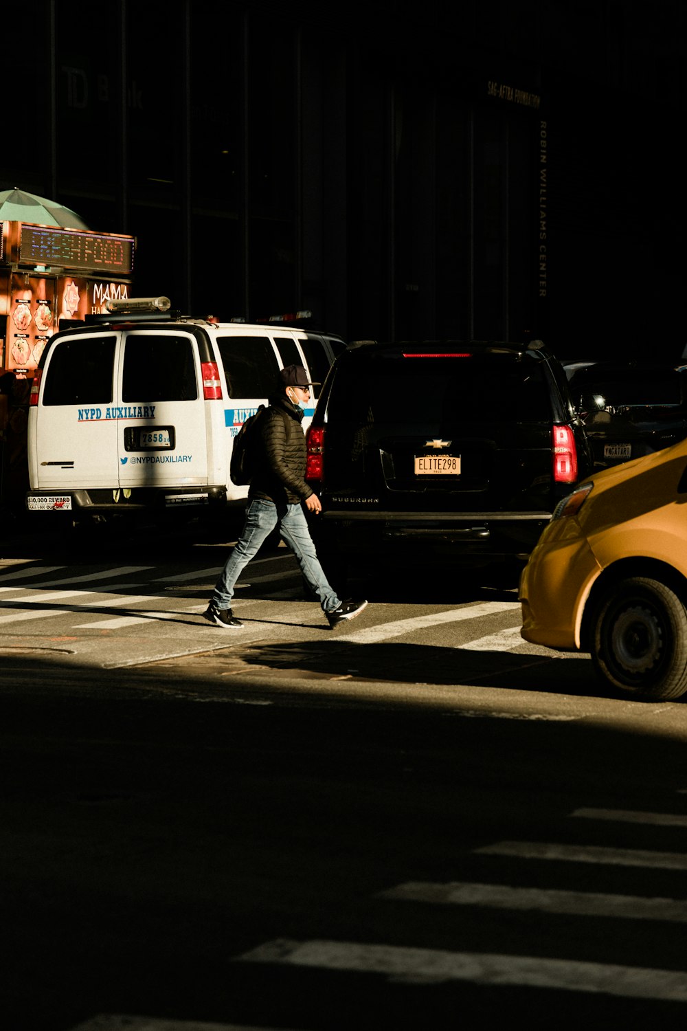 a man walking across a cross walk at night