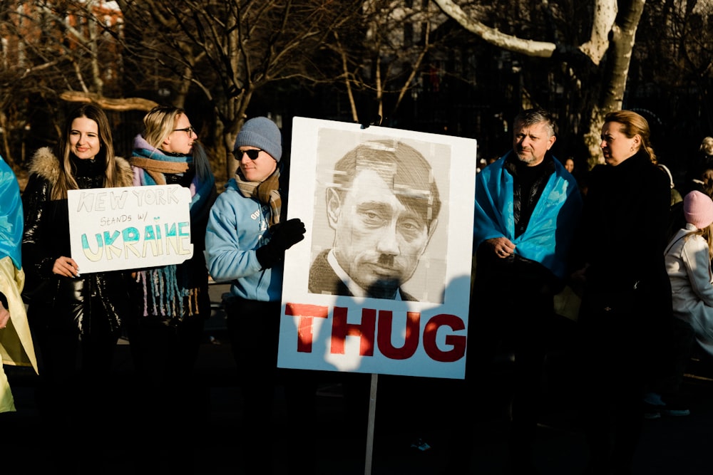 a group of people holding a sign with a picture of a man