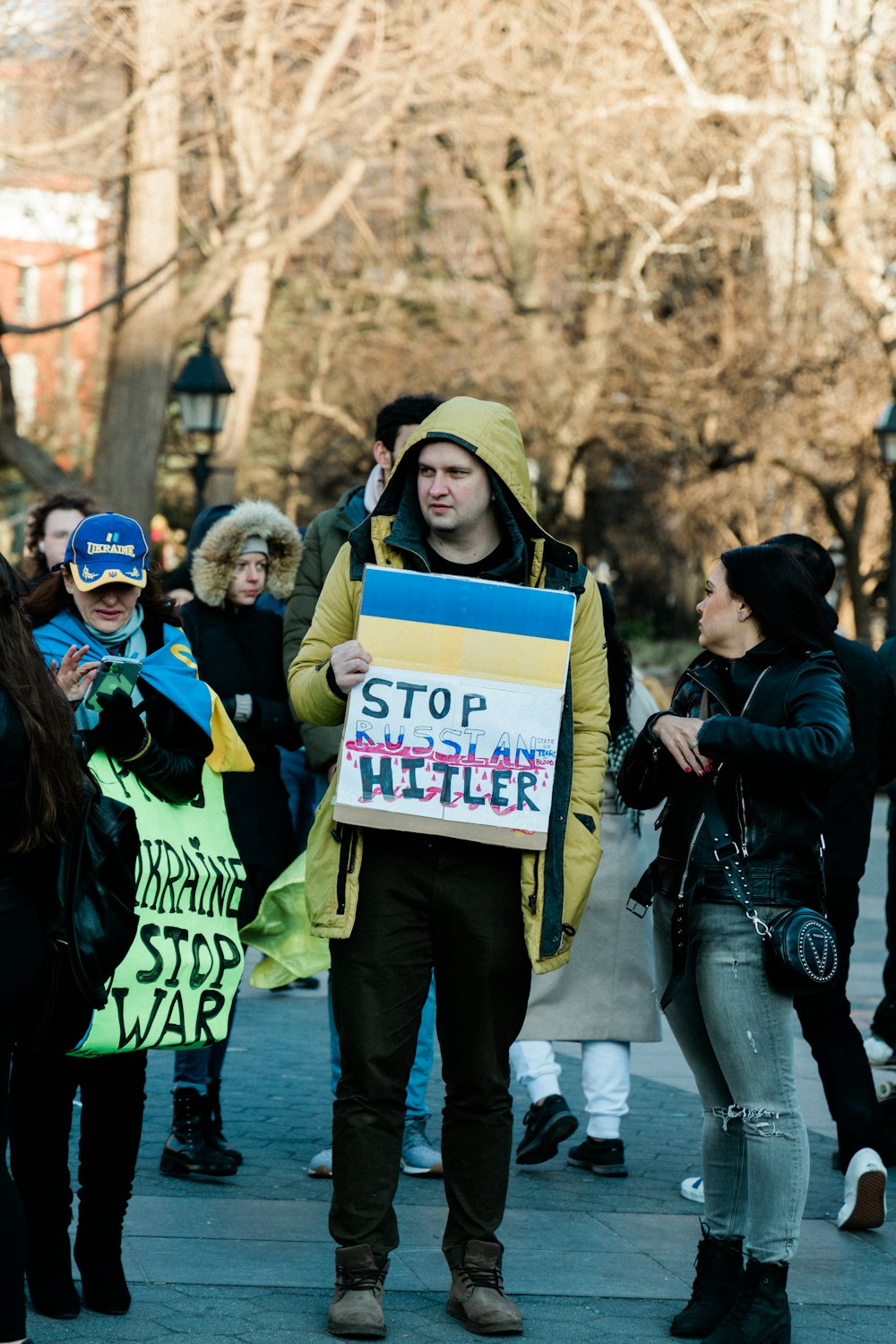 Un hombre con una chaqueta amarilla sosteniendo un cartel