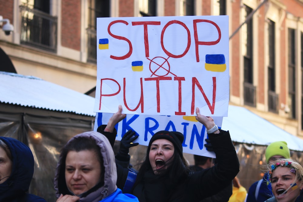 Un grupo de personas sosteniendo un cartel que dice stop and puttin